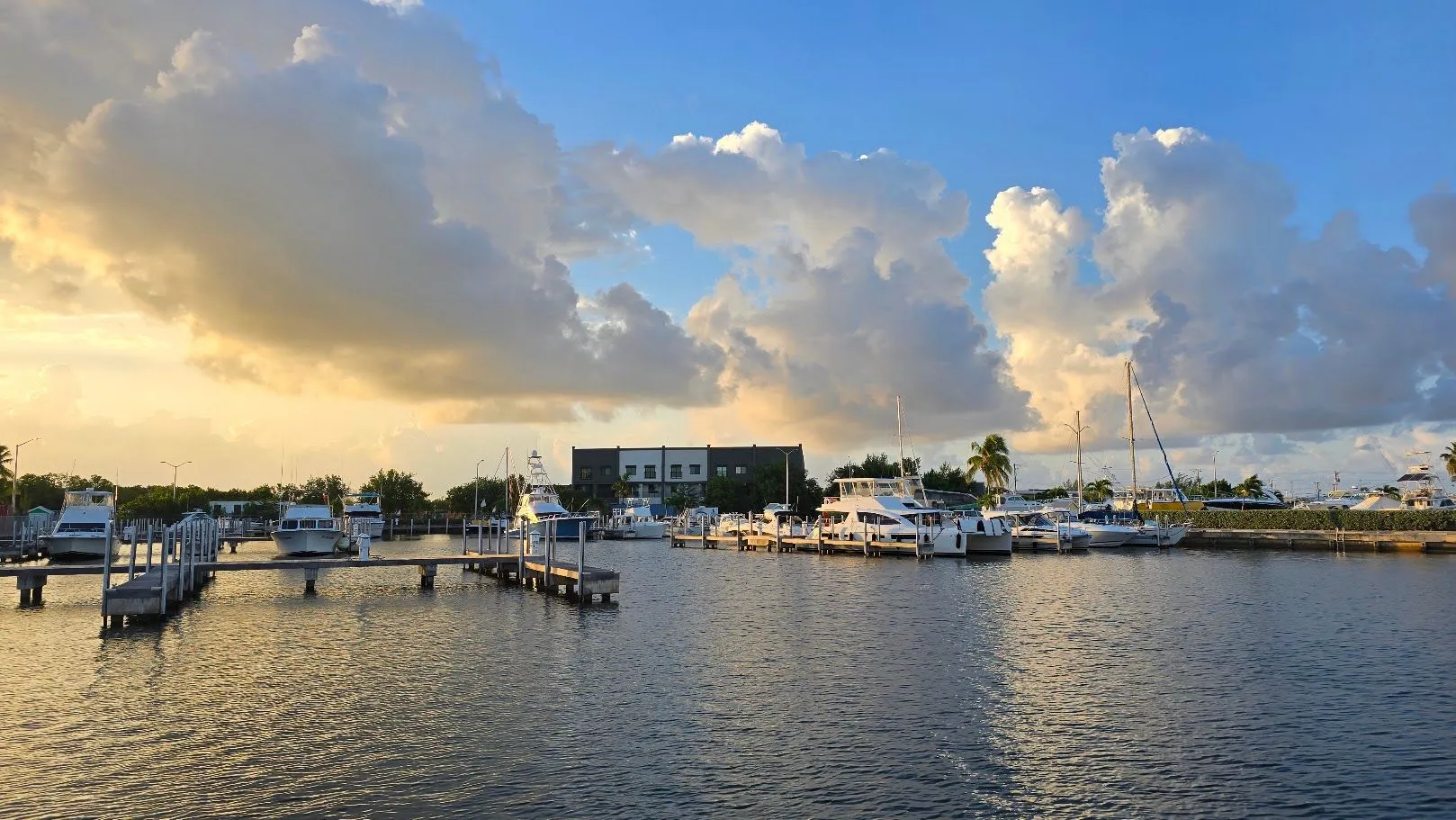 Boats moored at a marina at sunrise beneath dramatic clouds
